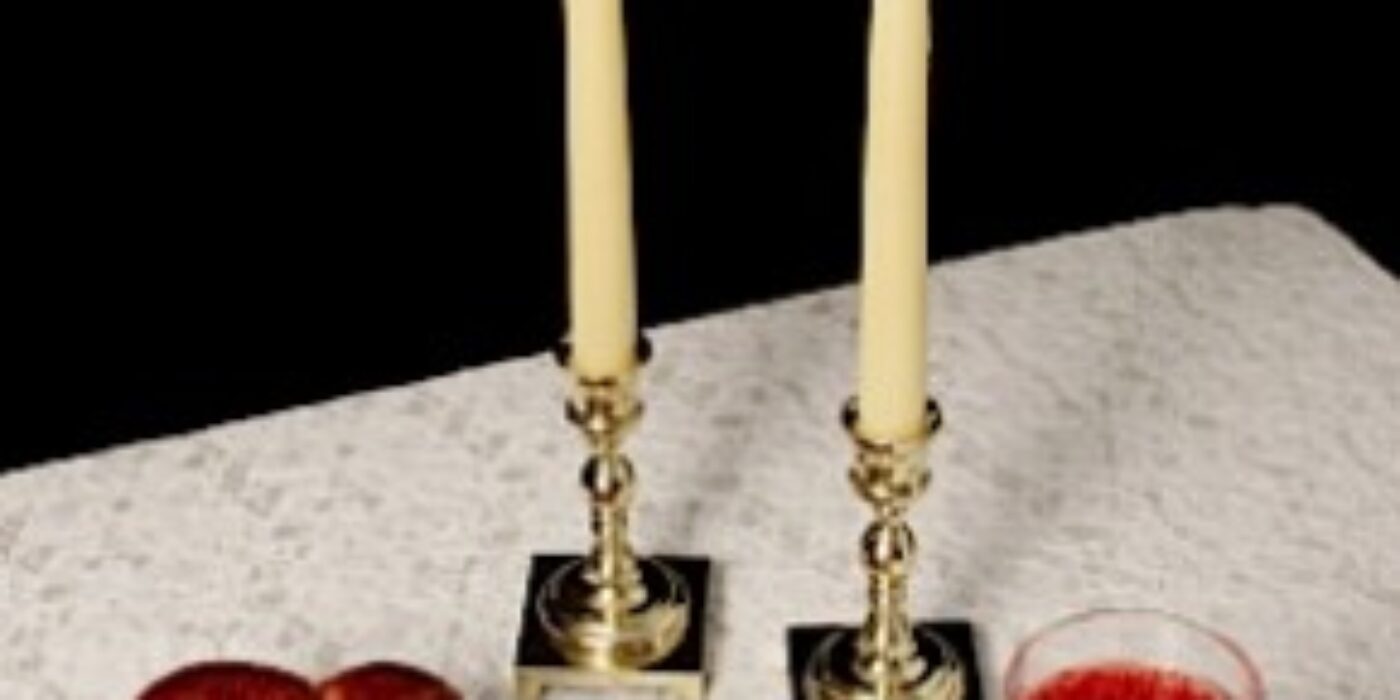 Challah, candlesticks, wine on white tablecloth